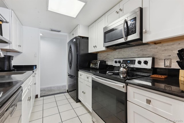 kitchen featuring light tile patterned flooring, appliances with stainless steel finishes, white cabinets, and backsplash