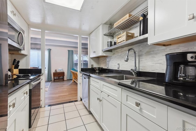 kitchen with white cabinetry, sink, light tile patterned floors, and stainless steel appliances