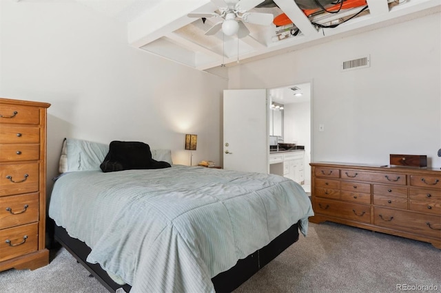 carpeted bedroom featuring ceiling fan, ensuite bathroom, and beam ceiling