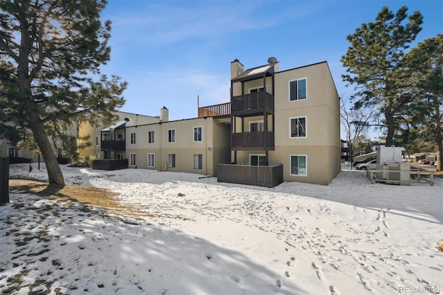 snow covered back of property with a balcony