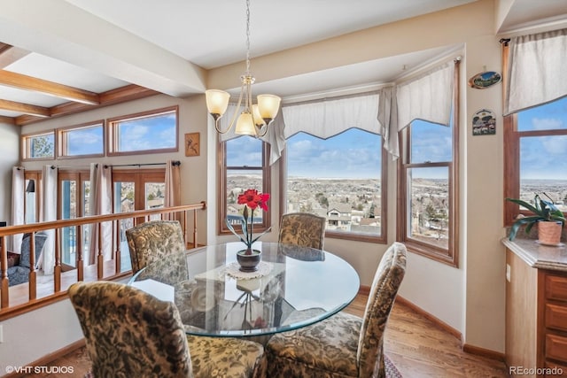 dining room with a chandelier, beamed ceiling, wood finished floors, and baseboards