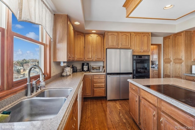 kitchen with dark wood-style floors, recessed lighting, brown cabinetry, a sink, and black appliances