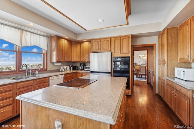 kitchen with white appliances, dark wood-style flooring, a kitchen island, a sink, and brown cabinets