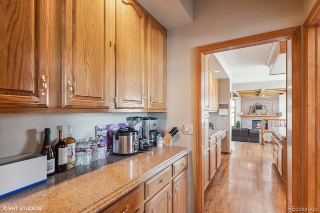 interior space with light wood-style flooring, light stone counters, and brown cabinetry