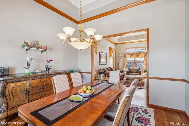 dining room featuring baseboards, a tray ceiling, a chandelier, and wood finished floors