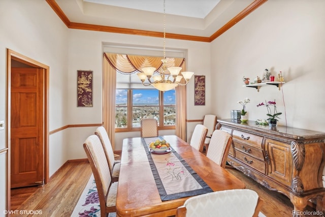 dining area featuring an inviting chandelier, crown molding, baseboards, and wood finished floors