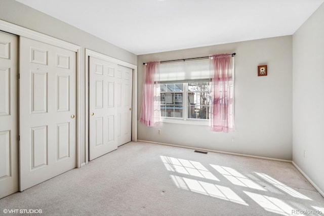 unfurnished bedroom featuring carpet, visible vents, and baseboards