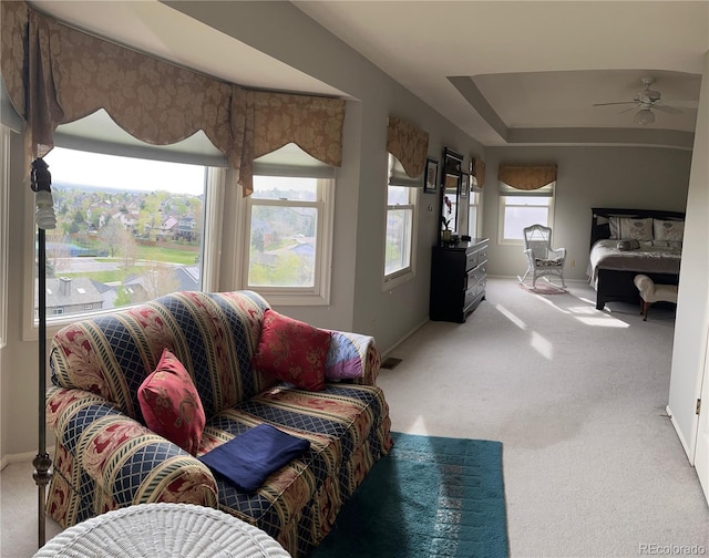 carpeted living room featuring a tray ceiling and baseboards