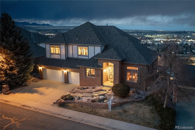 view of front of property featuring a garage, driveway, brick siding, and roof with shingles