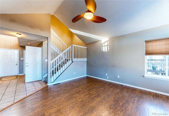 unfurnished living room featuring hardwood / wood-style floors, ceiling fan, a textured ceiling, and vaulted ceiling