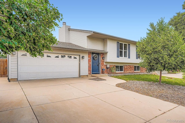 19196 E Kansas Dr, Aurora, CO 80017 - tri-level home featuring an attached garage, concrete driveway, brick siding, and a chimney