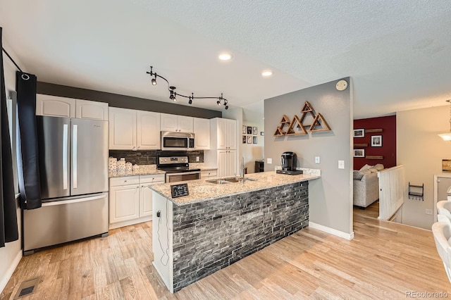 19196 E Kansas Dr, Aurora, CO 80017 - kitchen with appliances with stainless steel finishes, light wood-type flooring, white cabinets, light stone countertops, and tasteful backsplash