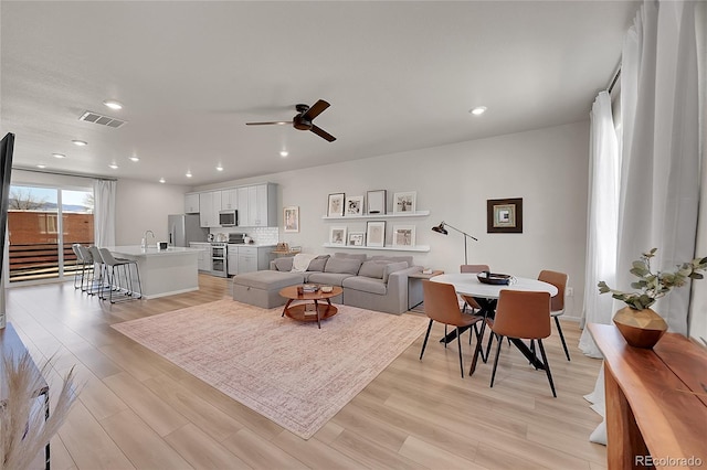 living room with a ceiling fan, visible vents, recessed lighting, and light wood-style floors