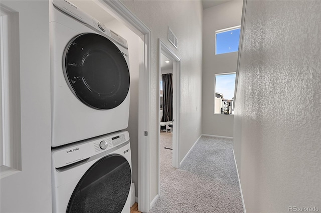 laundry area featuring baseboards, visible vents, stacked washer / drying machine, carpet floors, and laundry area