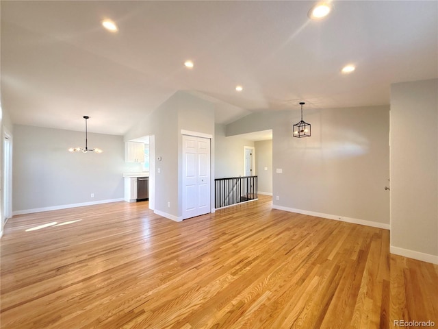 empty room featuring a chandelier, light wood-type flooring, and lofted ceiling