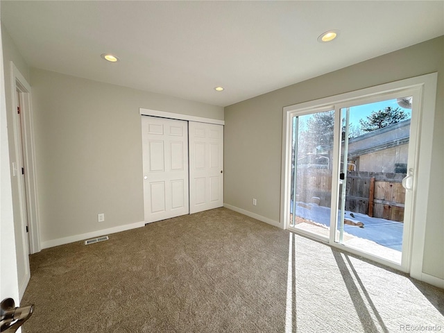 unfurnished bedroom featuring access to exterior, carpet, and a closet