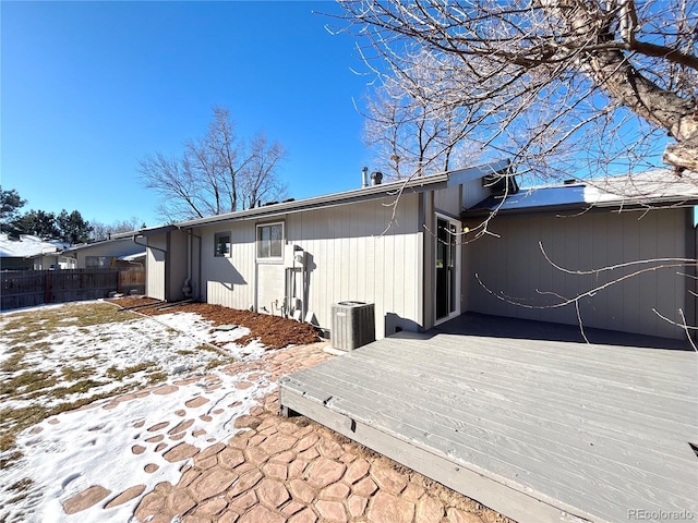 snow covered house with central air condition unit and a deck