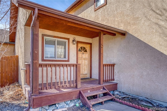 property entrance featuring stucco siding and fence