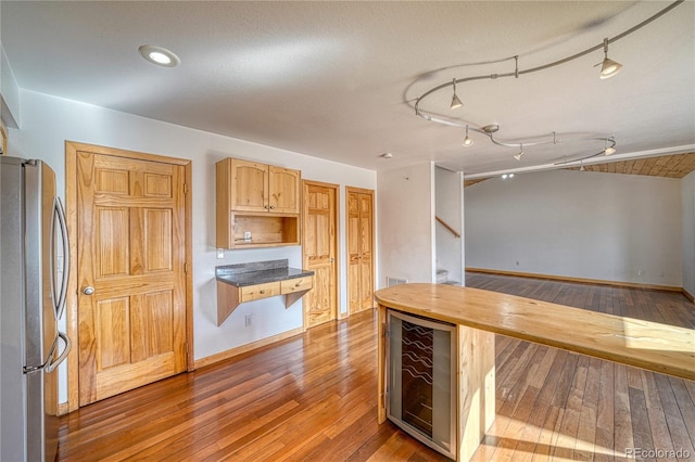 kitchen with wine cooler, freestanding refrigerator, wood-type flooring, wooden counters, and track lighting