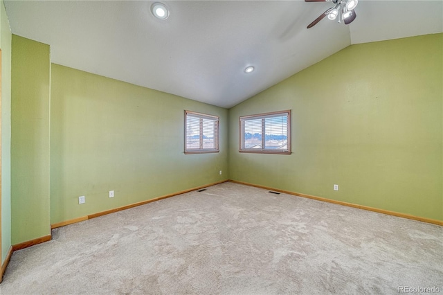 carpeted empty room with visible vents, baseboards, lofted ceiling, and ceiling fan