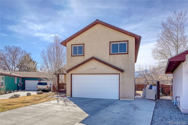 view of front of house with a gate, concrete driveway, stucco siding, fence, and an attached garage