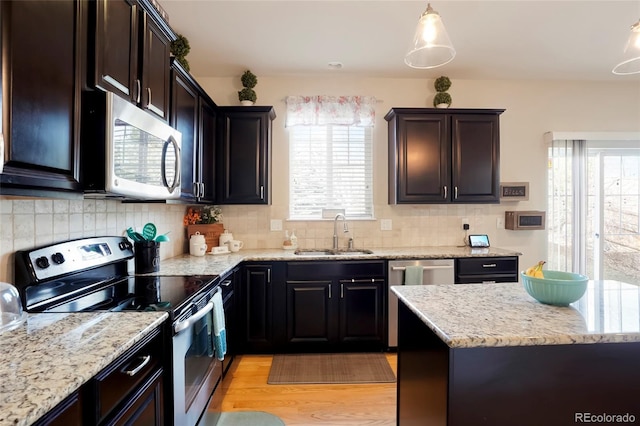 kitchen with a sink, light stone countertops, backsplash, and stainless steel appliances