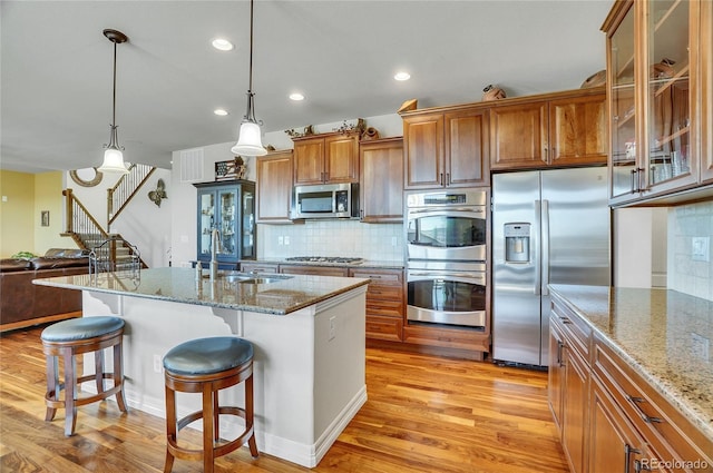 kitchen featuring pendant lighting, stainless steel appliances, sink, backsplash, and a breakfast bar