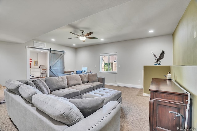 living room featuring ceiling fan, light carpet, and a barn door