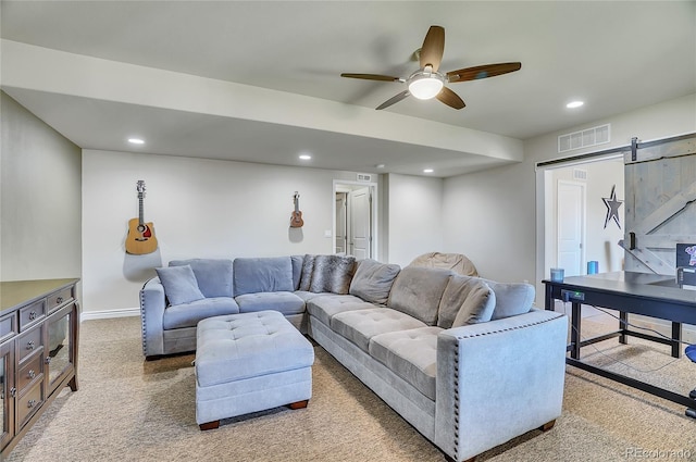 carpeted living room with ceiling fan and a barn door