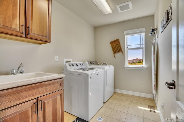 laundry area with light tile patterned floors, sink, washing machine and clothes dryer, and cabinets