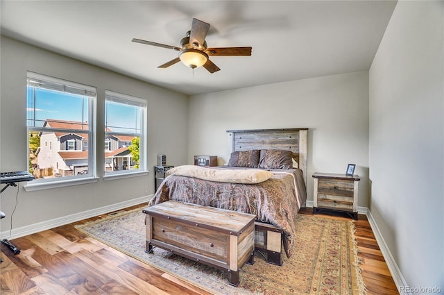 bedroom featuring a ceiling fan, baseboards, and wood finished floors