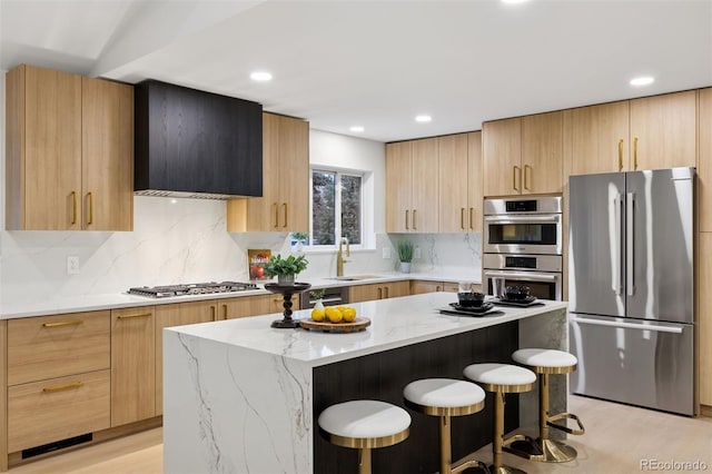 kitchen featuring light stone counters, a sink, appliances with stainless steel finishes, modern cabinets, and a kitchen bar