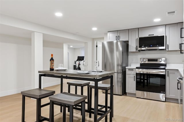 kitchen featuring stainless steel appliances, light wood-type flooring, and gray cabinets