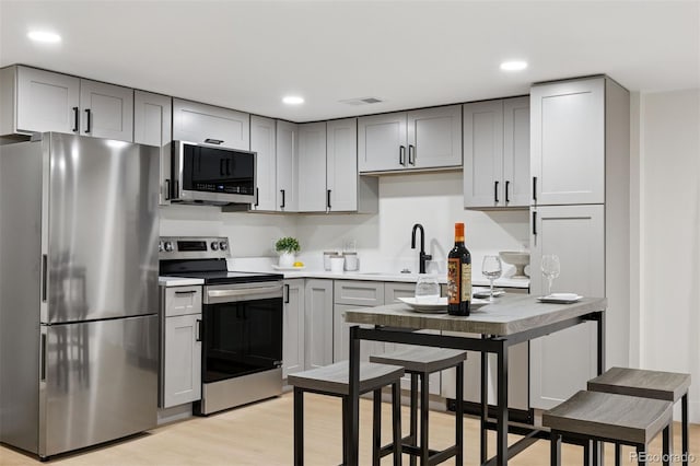 kitchen featuring light wood finished floors, visible vents, stainless steel appliances, and gray cabinetry