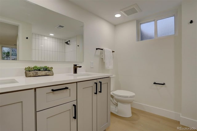 full bath featuring toilet, visible vents, a sink, and wood finished floors