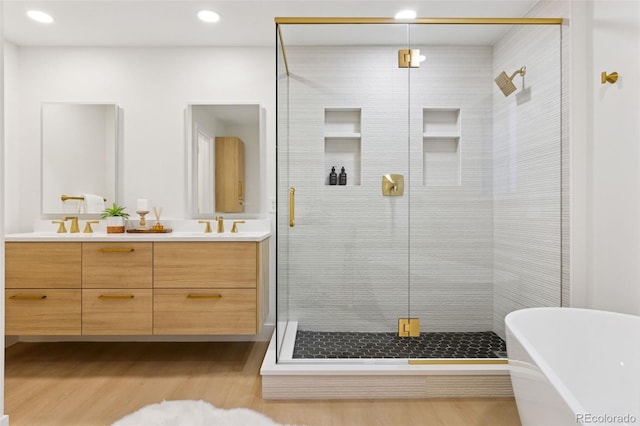 full bathroom featuring double vanity, a soaking tub, a shower stall, and wood finished floors