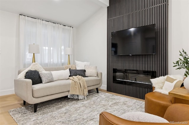 living room with a glass covered fireplace, lofted ceiling with beams, baseboards, and wood finished floors