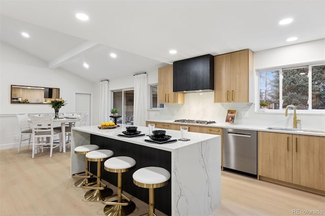 kitchen with modern cabinets, appliances with stainless steel finishes, a breakfast bar, vaulted ceiling with beams, and a sink