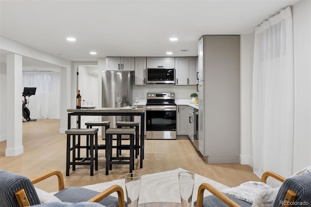 kitchen with gray cabinets, stainless steel appliances, light countertops, light wood-style floors, and recessed lighting