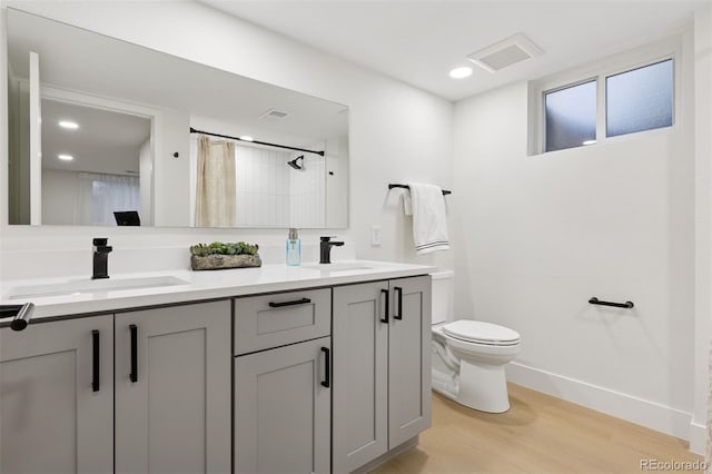 bathroom with toilet, visible vents, a sink, and wood finished floors