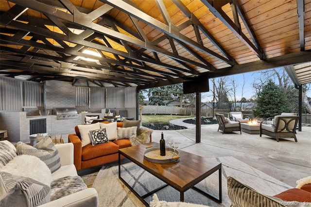 view of patio / terrace featuring exterior kitchen, an outdoor living space with a fire pit, a grill, and fence