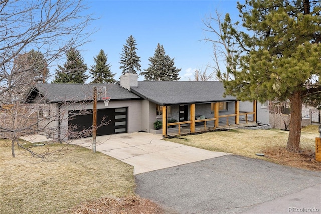 view of front of house featuring a porch, a garage, driveway, a front lawn, and a chimney