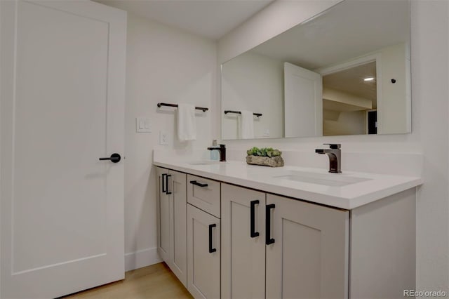 bathroom with double vanity, a sink, and wood finished floors