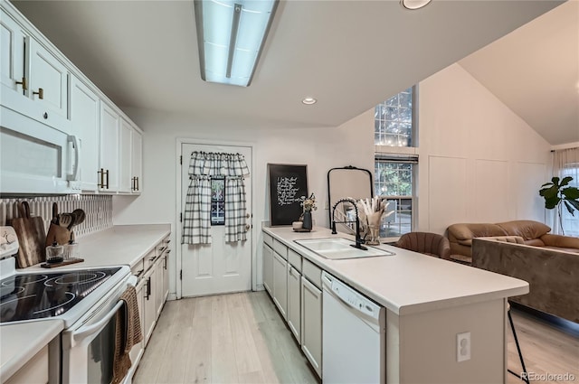 kitchen featuring light wood-type flooring, a sink, a peninsula, and white appliances