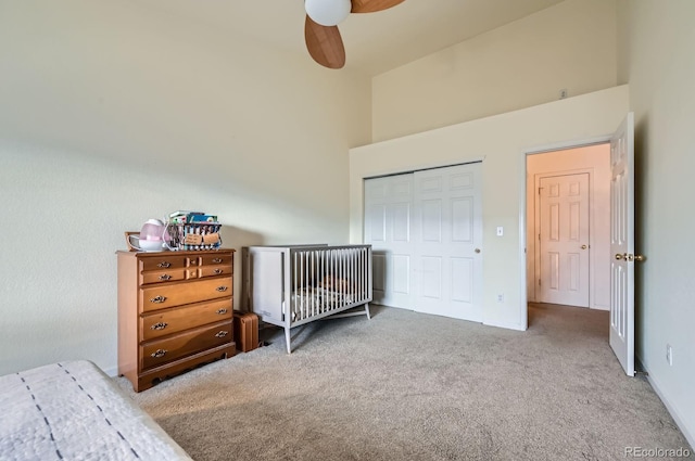 carpeted bedroom with a closet, a ceiling fan, and a towering ceiling