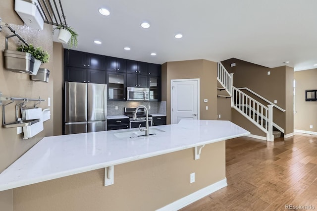 11323 Uptown Ave, Broomfield, CO 80021 - kitchen featuring a sink, dark cabinetry, wood finished floors, appliances with stainless steel finishes, and a breakfast bar area