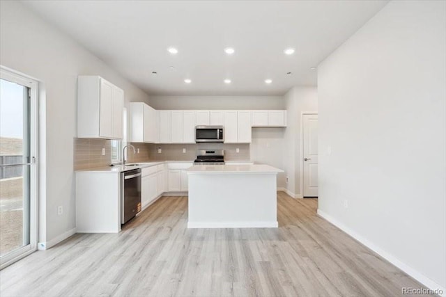 kitchen featuring appliances with stainless steel finishes, decorative backsplash, and light wood-type flooring