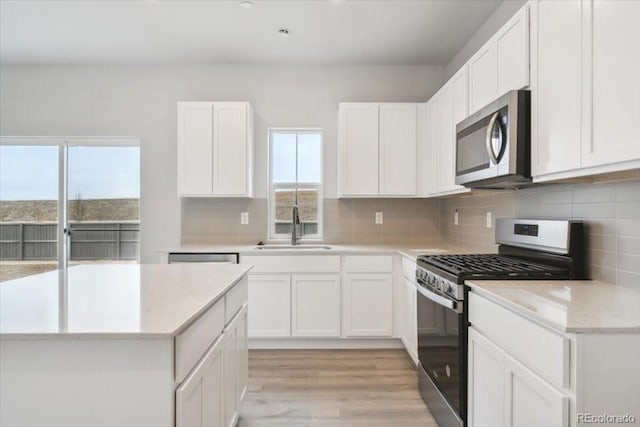 kitchen featuring light wood-type flooring, white cabinetry, appliances with stainless steel finishes, and a sink
