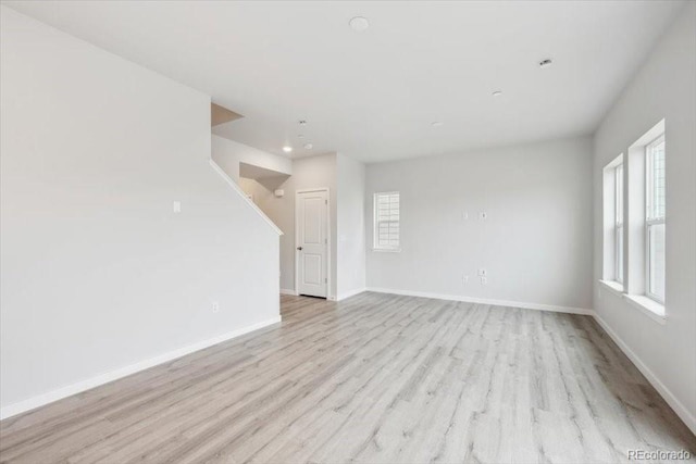 unfurnished living room with recessed lighting, baseboards, and light wood-style floors