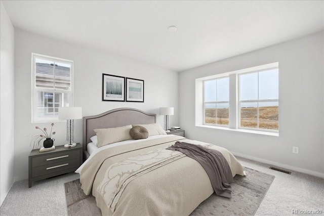 bedroom with light colored carpet, baseboards, visible vents, and multiple windows